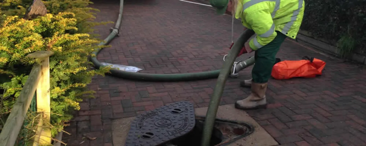 Septic tank cleaning technician servicing a septic tank with a vacuum hose in Boise, ID