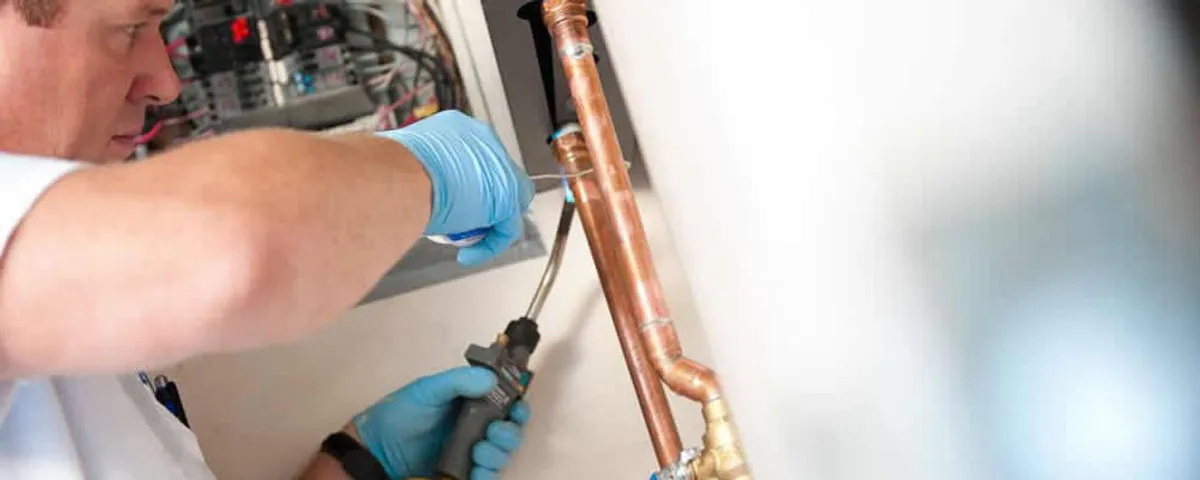 Water heater repair technician testing copper pipe connections and controls in Boise, ID